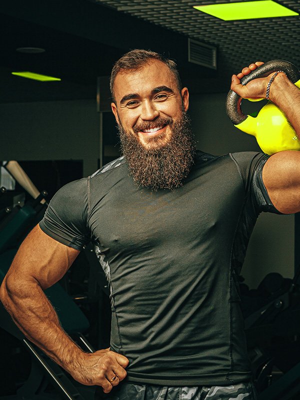 Smiling senior man lifting a barbell indoors.